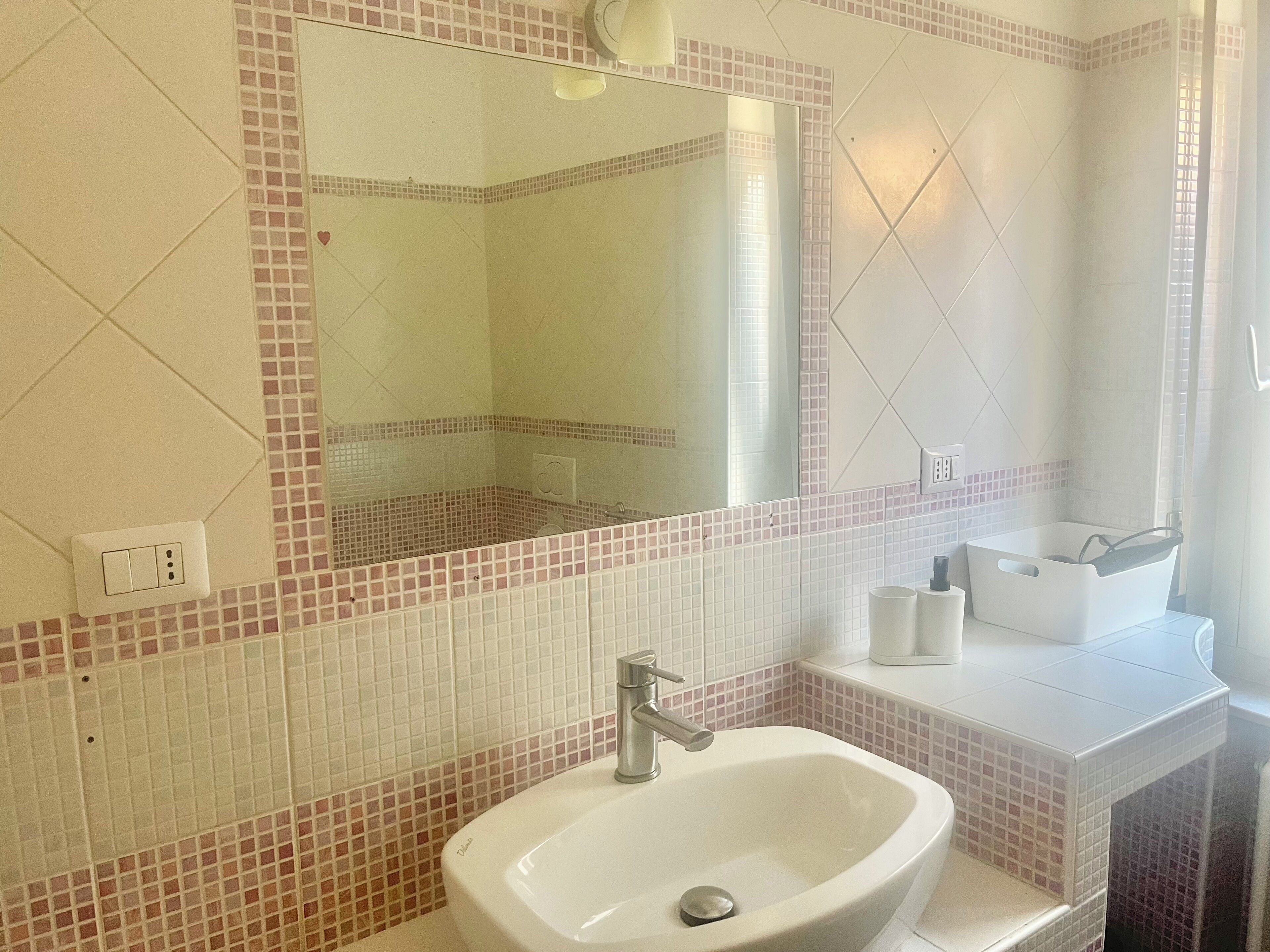 A bathroom with a white sink, a mirror, and a tiled backsplash.