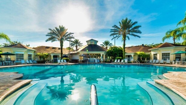 A swimming pool with lounge chairs and palm trees.