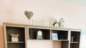 A living room with a TV on a wooden stand, surrounded by shelves with books and decorative items.