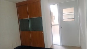 Ein Zimmer mit einer Holztür, einer weißen Tür mit Milchglasfenster und einem Fliesenboden.