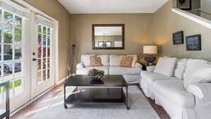 A living room with a white sofa, a dark coffee table, and a large mirror on the wall.