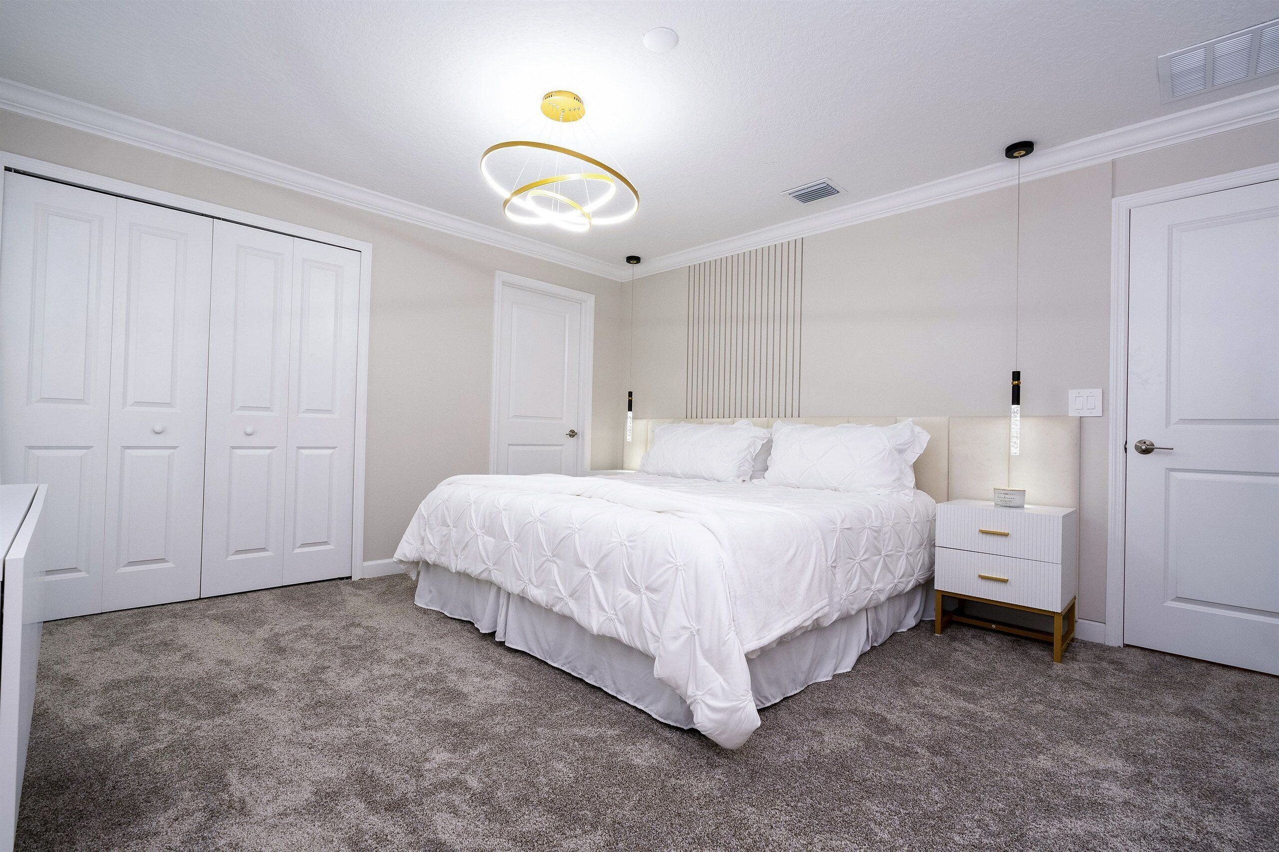 A bedroom with a bed, nightstands, a dresser, and a closet.