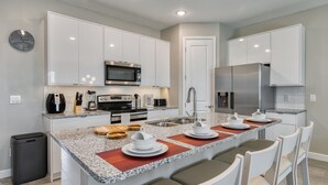 Una cocina moderna con armarios blancos, electrodomésticos de acero inoxidable y encimera de granito.