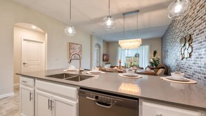 A modern kitchen with a large island, stainless steel appliances, and pendant lighting.