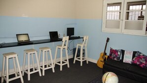 Ett rum med en svart soffa, en jordglob, en gitarr och en bardisk med barstolar och en bärbar dator.