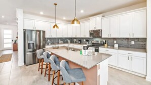 A modern kitchen with white cabinets, stainless steel appliances, and a central island with bar stools.