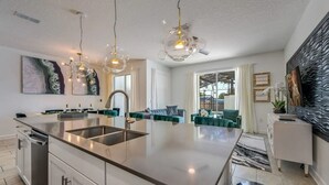 Een moderne keuken met een centraal eiland, roestvrijstalen apparatuur en hanglampen.