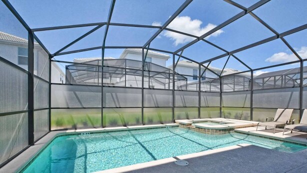 Une piscine extérieure couverte, dotée d’un jacuzzi, et entourée d’une structure métallique et de parois en treillis.