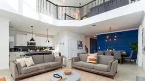 Un apartamento moderno con sala de estar que cuenta con dos sofás grises, una mesa de centro redonda y un comedor con una pared azul decorativa.