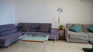 A living room with two sofas, a glass coffee table, a side table with a lamp, and a potted plant. - L'horizon bleu : Sea view, air-conditioning, swimming pool, near airport and hospital for 4 people (Saint-Denis)
