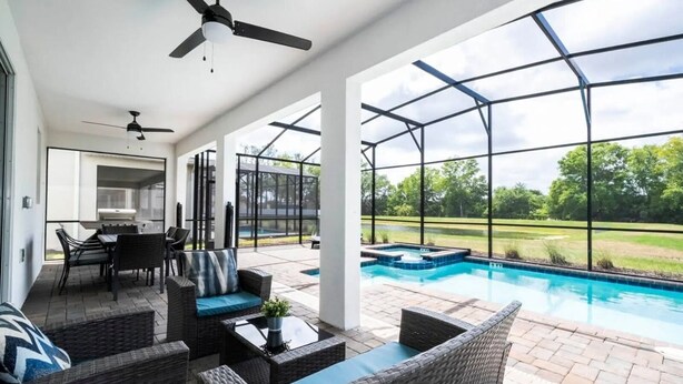 A covered patio area with outdoor furniture, a pool, and a view of the surrounding landscape.