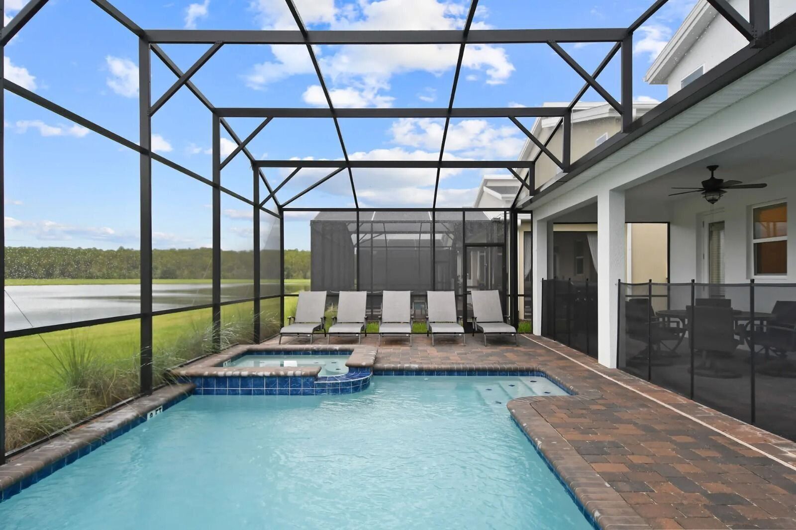 Une piscine couverte avec vue sur le paysage, un patio aménagé avec des sièges et un ventilateur de plafond.