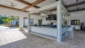 Un espace bar extérieur doté d’un comptoir, de guirlandes lumineuses et de ventilateurs de plafond.