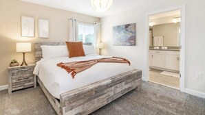 Une chambre avec un lit en bois, des tables de chevet, une lampe et une vue sur la cuisine.