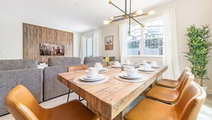 Un coin repas avec une table en bois dressée pour quatre personnes, entourée de fauteuils en cuir.