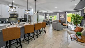 A modern kitchen with a central island, bar stools, and pendant lighting. - Themed Home w/ Pool at Storey Lake (kissimmee)
