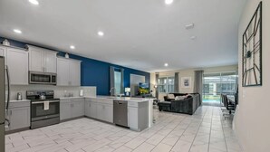 Une cuisine moderne avec des meubles blancs, un îlot central et un coin repas comprenant un canapé et une table.