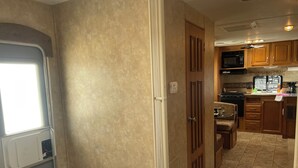 A compact RV kitchen with wooden cabinets, a microwave, and a stove.