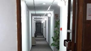 A long, narrow hallway with a carpeted floor, white walls, and a door at the end. - Hotel Mora (Puerto Madryn)