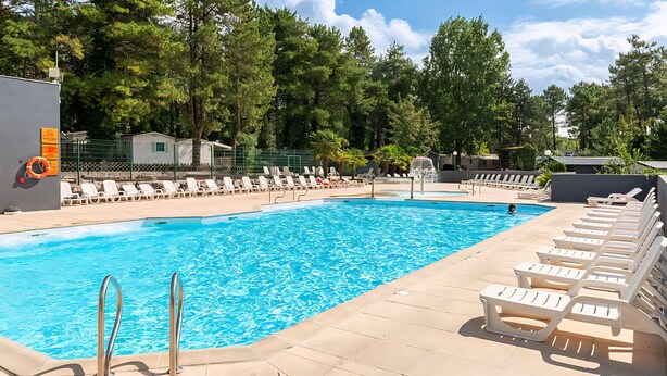 Une piscine avec des chaises longues et une bouée de sauvetage sur le bord.