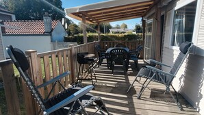 Une terrasse en bois, agréée de mobilier d’extérieur, notamment une table et des chaises, et surmontée d’une pergola.