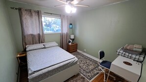 A bedroom with a bed, a desk, a chair, a ceiling fan, and a window. - Private Room at Riverfront House (Kamloops)
