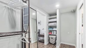 A walk-in closet with a metal drying rack, shelves with folded linens, and a trash bin. - Chic & Stylish Midtown PHX Condo Retreat - Stunning Views & Light Rail Access (Phoenix)