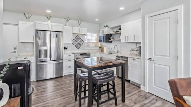 A modern kitchen with white cabinets, stainless steel appliances, and a central island with stools. - Chic & Stylish Midtown PHX Condo Retreat - Stunning Views & Light Rail Access (Phoenix)