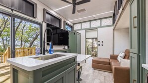 A modern kitchen with a large island, a built-in oven, and a ceiling fan. - Private Lakeside RV Escape with Hot Tub, Multi-Level Deck, & Easy Water Access (Corsicana)