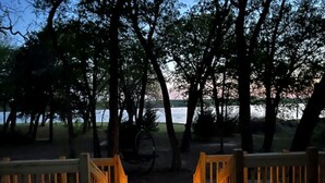 A wooden deck with railings leading to a body of water, surrounded by trees. - Private Lakeside RV Escape with Hot Tub, Multi-Level Deck, & Easy Water Access (Corsicana)