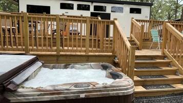 Un jacuzzi, terraza de madera y un edificio con ventanas.