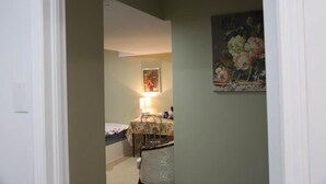 A narrow hallway with a bed and a table in the background. - Ivy Den (Oakville)