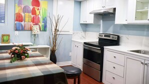 A modern kitchen with white cabinets, a black stove, and a marble backsplash. - Ivy Den (Oakville)