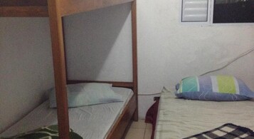 A bunk bed with a wooden frame and a single bed with a colorful pillow.