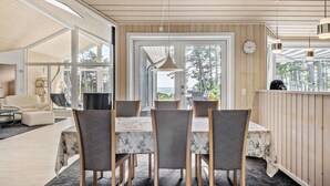Een eetgedeelte met een tafel en stoelen, een uitzicht op de omgeving en een houten plafond.