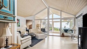 Een ruime woonkamer met een hoge plafond, een groot raam en uitzicht op de omgeving.