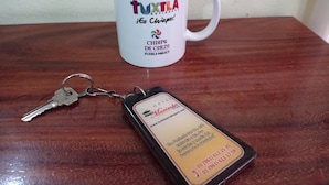 A white mug with text and a keychain with a hotel name and address. - Marimba Park (Tuxtla Gutierrez)