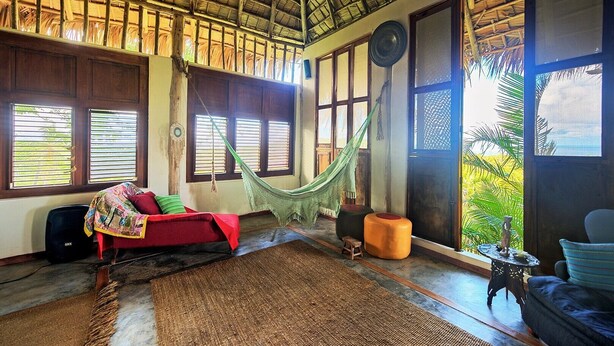 Una habitación con una hamaca, un sofá rojo y vistas al exterior.