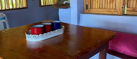 A wooden table with a lace table runner and a tray of red, blue, and white cups.