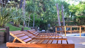A wooden deck with lounge chairs and a wooden table. - Alamos Hosteria (Mar Azul)