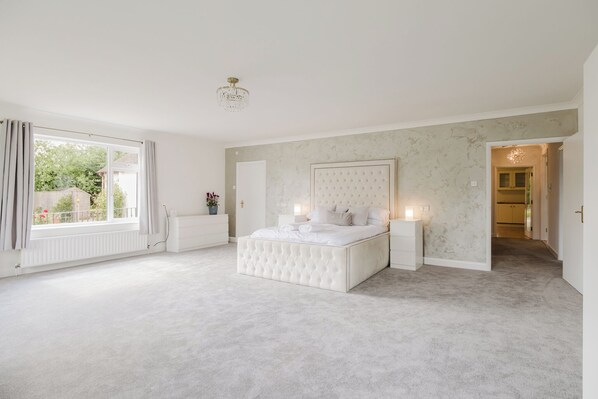 A bedroom with a large bed, bedside lamps, a radiator, and a view of the outside. - Countryside Escape in Oxfordshire (Witney)