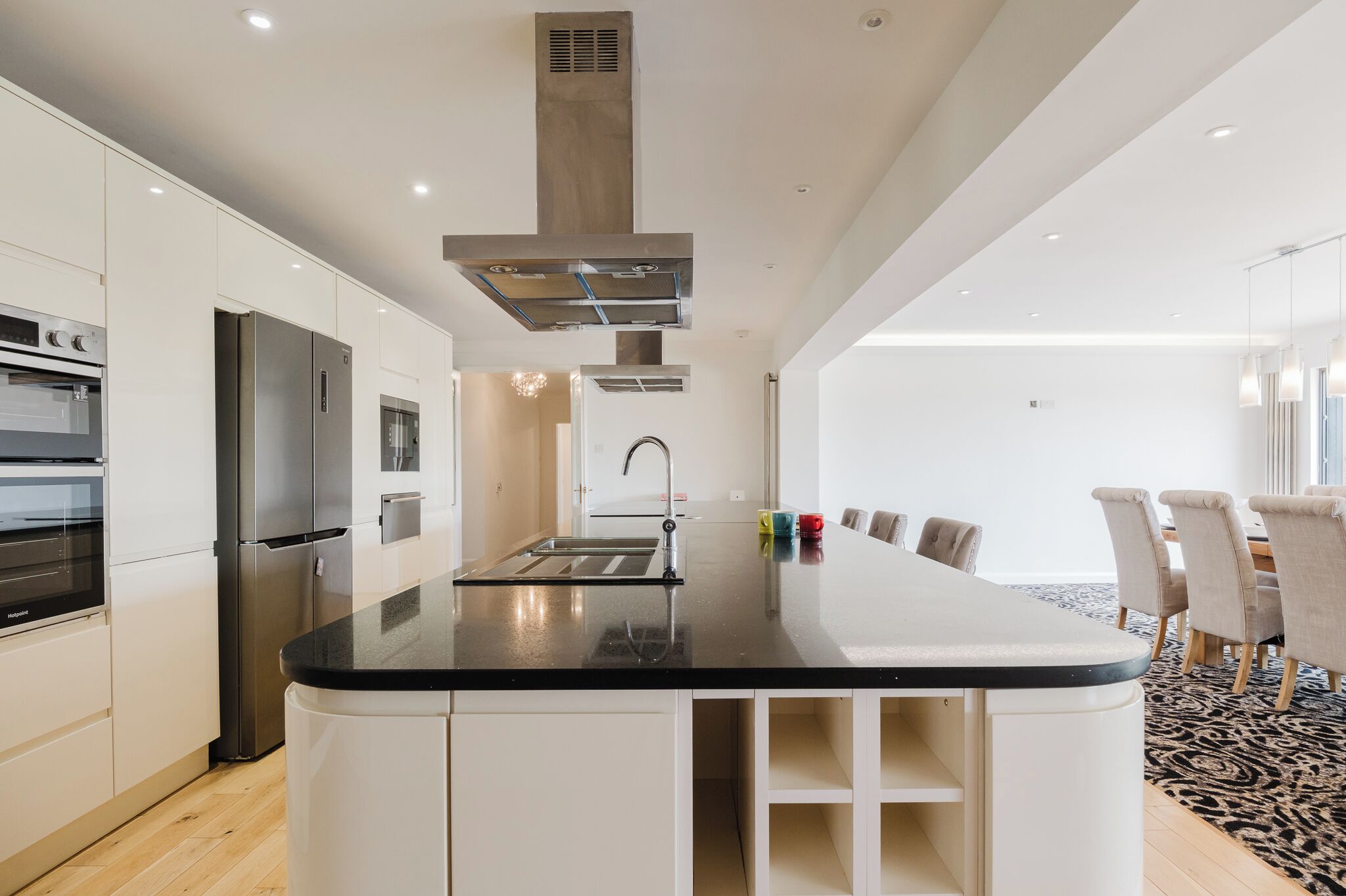 A modern kitchen with stainless steel appliances, a central island, and a dining area with a patterned rug.