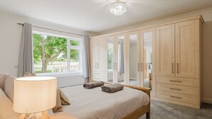 Um quarto com cama, abajur, guarda-roupa e janela com cortinas.