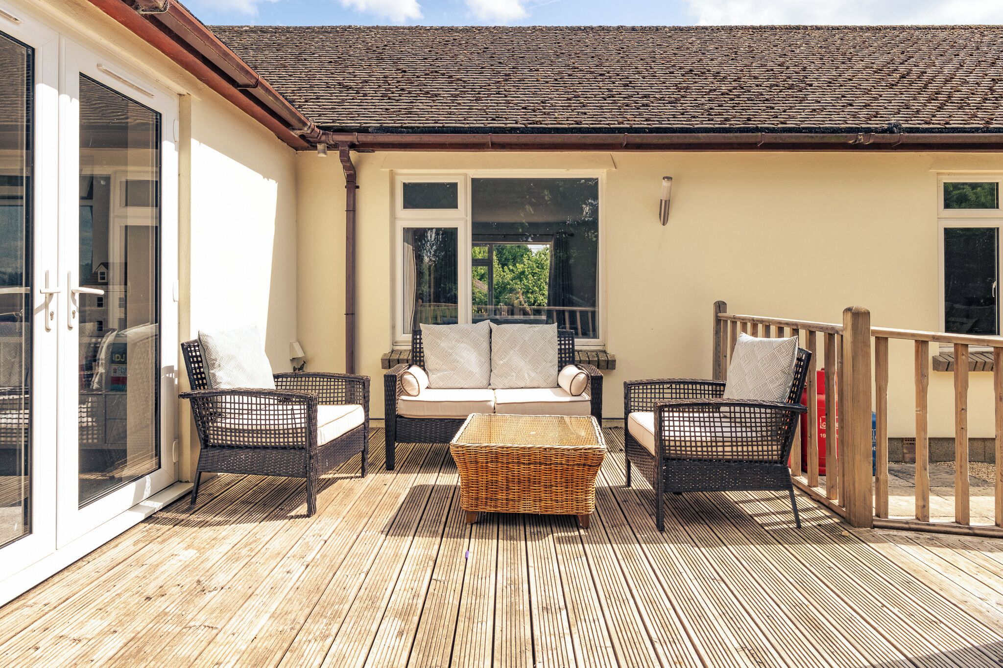 An outdoor patio with wicker furniture, a sofa, and a wooden deck.