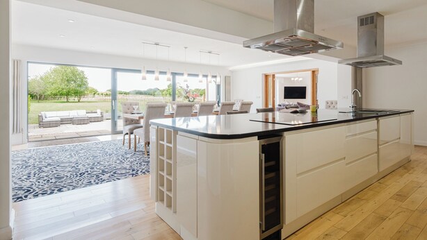 Uma cozinha moderna com uma ilha grande, eletrodomésticos embutidos e vista para um pátio.