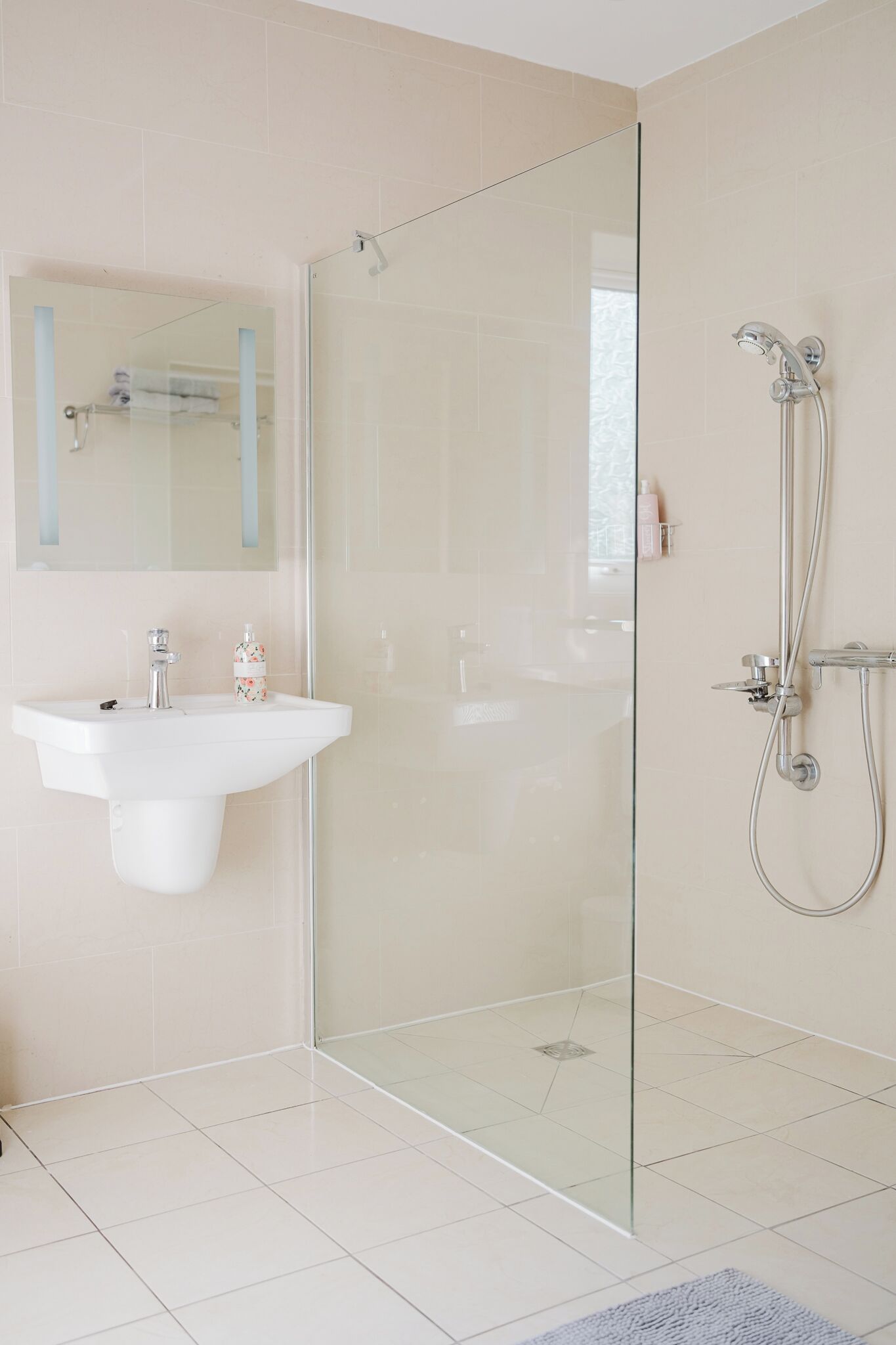 A modern bathroom with a glass-enclosed shower, a white sink, and a mirror above the sink.