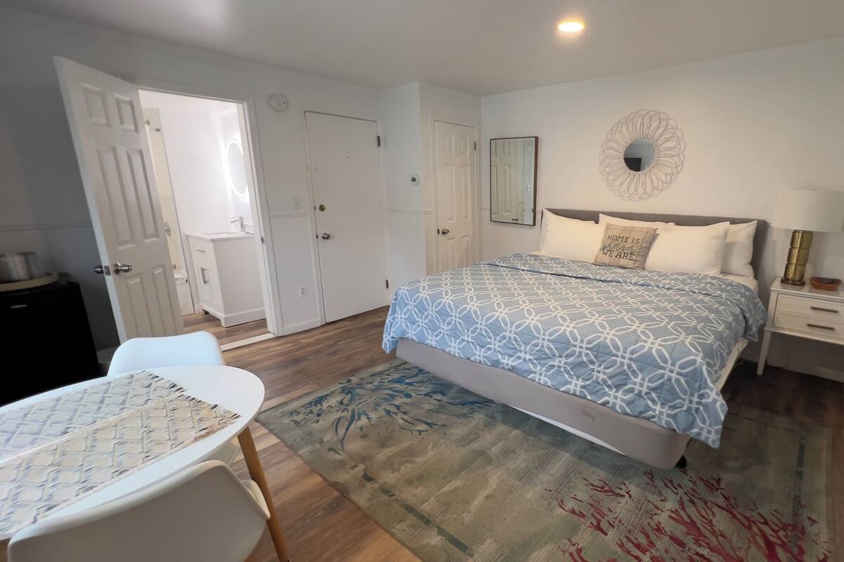A bedroom with a bed, bedside tables, a chair, a rug, and a door.