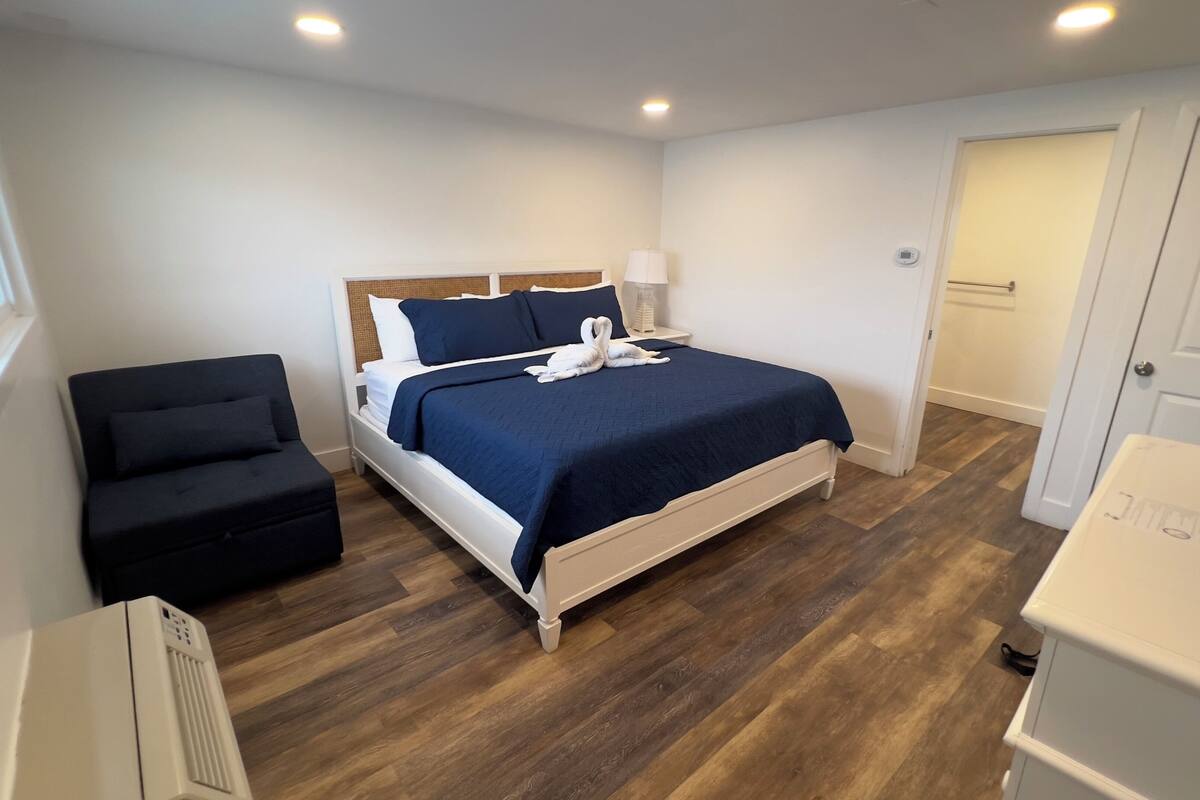 A bedroom with a bed, a chair, a bedside table, and a wardrobe.