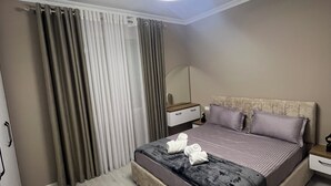 Une chambre à coucher moderne avec un grand lit, une table de chevet, une commode, un miroir et un luminaire au plafond.