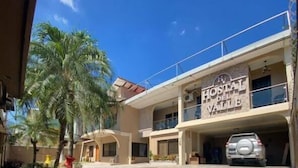 Un hotel llamado "Hotel del Valle" con un estacionamiento y una palmera en primer plano.